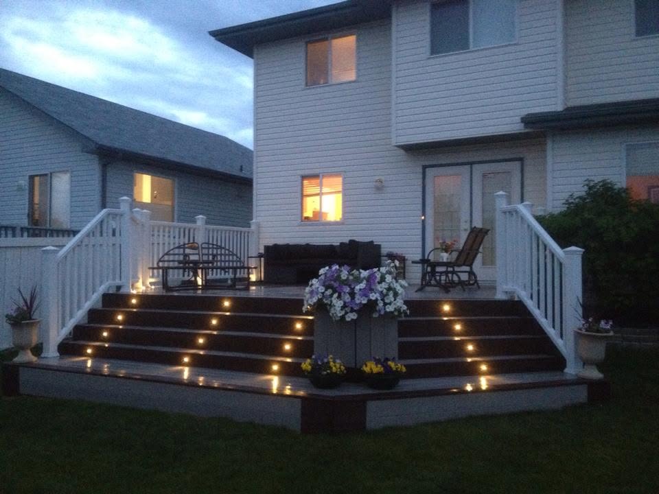 Backyard deck with white railings and built-in step lighting at dusk